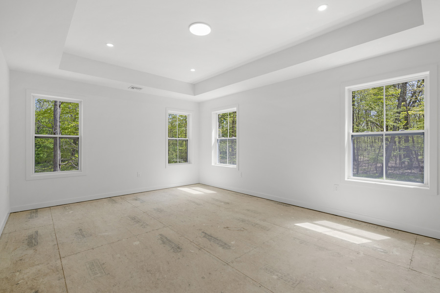 Elegant primary bedroom with double door entry, tray ceiling,, two walk-in closets and ensuite bath.  The Millbrook on Homesite 5 at Hidden Glen, Millbrook, NY